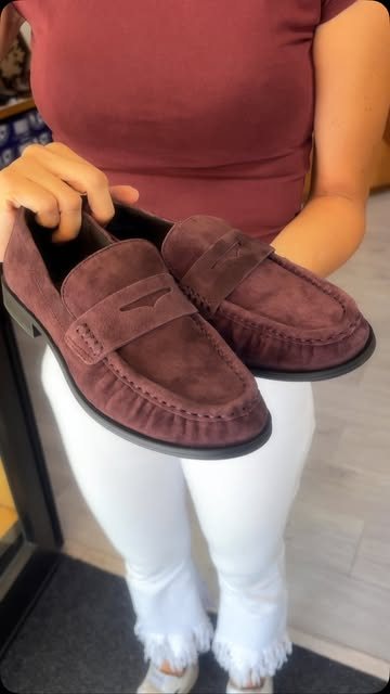 Mocassini in camoscio bordeaux tenuti in mano in negozio