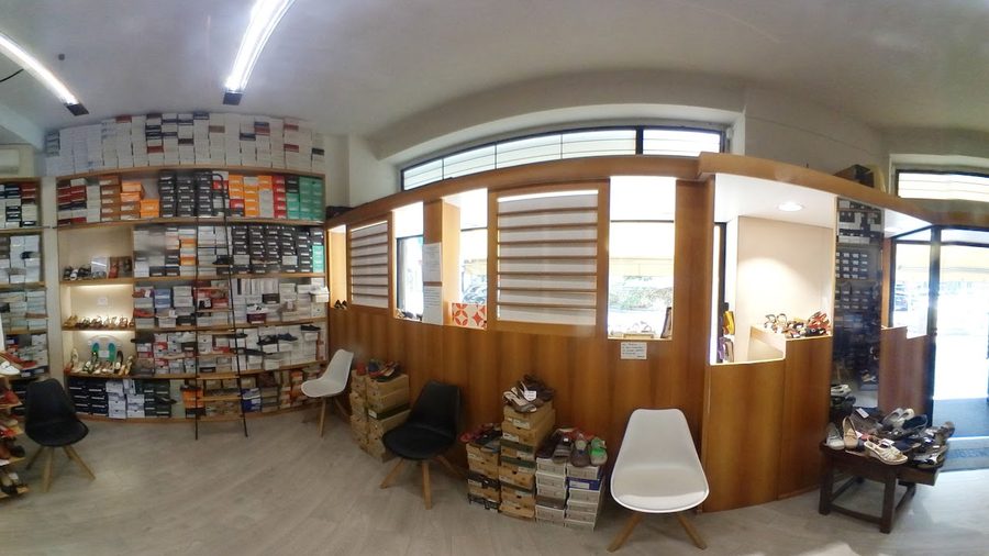 Interno del negozio: scaffali di scatole di scarpe, banco in legno e sedute per la prova