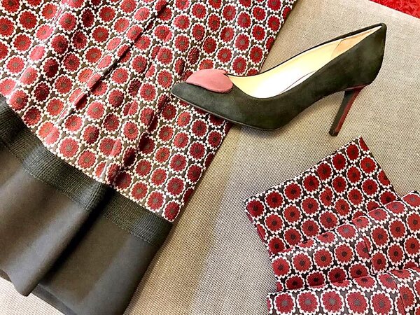 Décolleté in camoscio verde scuro con dettaglio bordeaux, su un tessuto a motivi geometrici