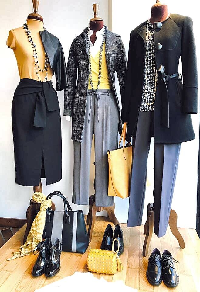 Vetrina con tre total look, borse gialla e nera, foulard e scarpe in vernice