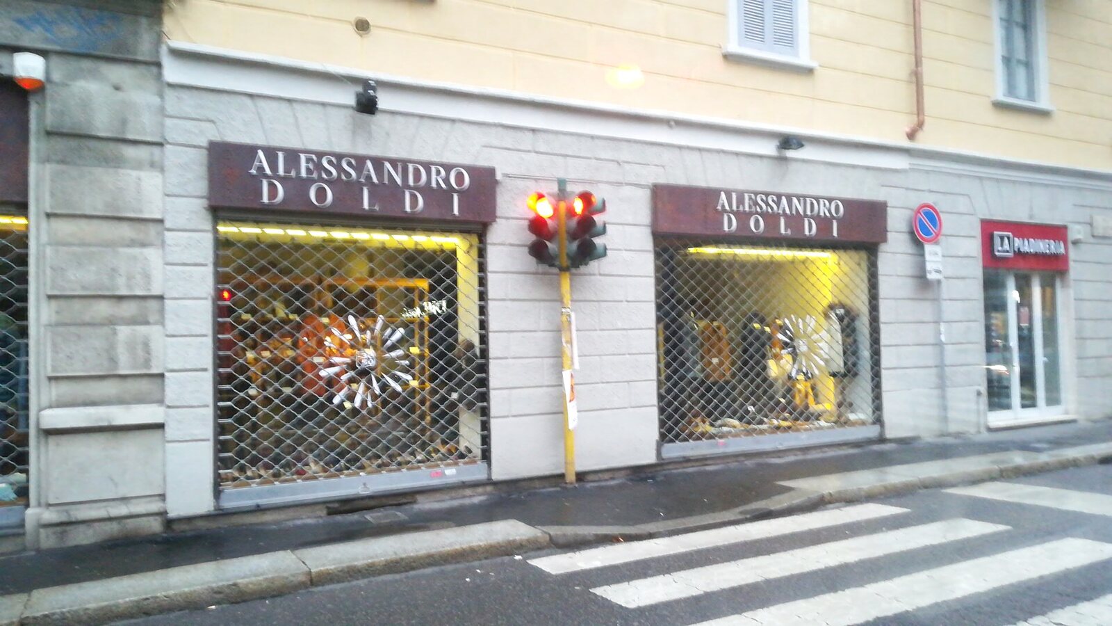 Le due vetrine illuminate di Alessandro Doldi in Via Luigi Canonica, con le insegne bordeaux